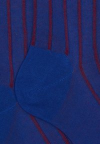 Calzini blu con sottili strisce rosse verticali e una sezione del tallone blu uniforme, mostrati da vicino.