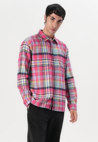 Red and blue plaid flannel shirt with yellow and green accents, button-up design, long sleeves, and a chest pocket; soft texture.