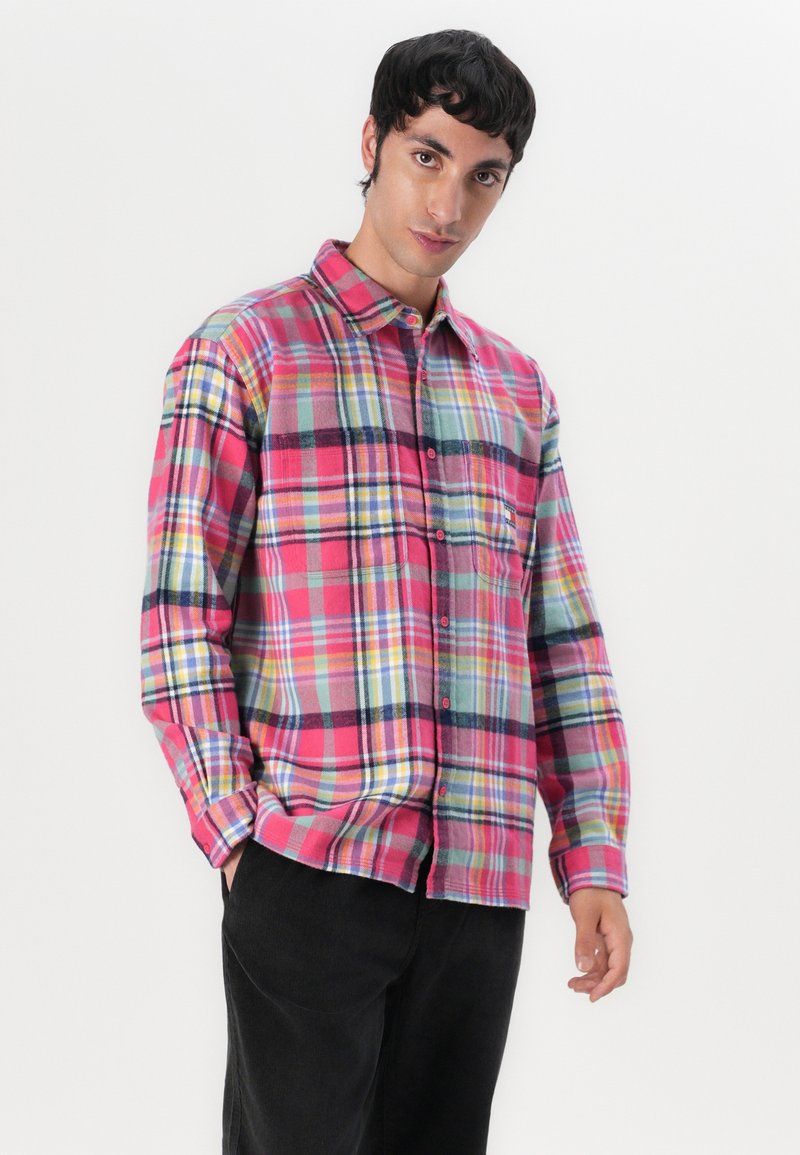 Rood en blauw geruit flanellen shirt met gele en groene accenten, knoopsluiting, lange mouwen en een borstzak; zachte textuur.