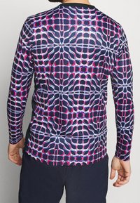 Košile s dlouhým rukávem s námořnickým základem a geometrickým vzorem v růžové a bílé barvě, vyrobená z hladkého a pružného materiálu.
