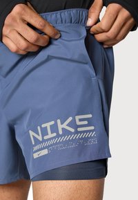 Nike-shorts i lyst blått stoff med glatt tekstur. Har sidelomme, elastisk midjebånd og reflekterende logodetaljer.