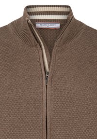 Bruine zip-up trui met een gestructureerd honingraatpatroon, geribde kraag en een gestreepte binnentoevoeging. Merkenlabel zichtbaar binnenin de kraag.