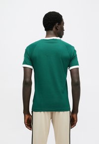 Πράσινο κοντομάνικο πουκάμισο με στρογγυλή λαιμόκοψη, λευκή επένδυση στις μανσέτες και το γιακά, με ομαλή υφή και εφαρμοστή σχεδίαση.