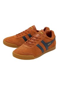 Sneaker in suede marrone con due strisce navy, suola in gomma e logo dorato di lato. Punta arrotondata e suola testurizzata. Design casual.