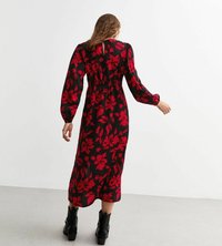 Czarna sukienka w czerwony kwiatowy wzór, z długimi rękawami z elastycznymi mankietami, dopasowany w pasie i o długości do kostek, zestawiona z czarnymi botkami na obcasie.