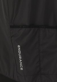 Sort atletisk jakke i letvægts, struktureret stof med et broderet "ENDURANCE" logo i hvidt langs siden og en lynlåslomme.