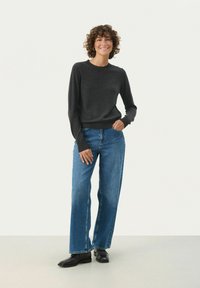 Mørkegrå strikket sweater med lange ærmer og rund hals, parret med lyseblå bredde jeans og sorte ankelstøvler.