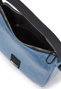 Denim shoulder bag with a black strap, zip closure, and silver hardware. Features a soft texture and interior black lining.