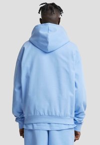 Lichtblauwe hoodie met een trekkoordcapuchon, zachte textuur en geribbelde manchetten. Heeft een comfortabele pasvorm en een boxy silhouet.