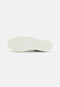 Fehér sneaker talp, mely textúrált gumiból készült, geometrikus mintákkal és domború "Buffalo" logóval rendelkezik. Kerek forma, barázdált tapadású dizájnnal.