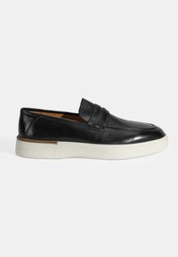 Zwarte leren instapper met een moccasin-stijl ontwerp, ronde neus en een witte rubberen zool. Heeft stikdetails en een decoratieve band.