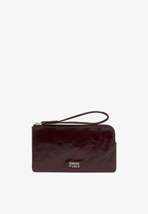 Burgundowa skórzana portmonetka o teksturowanym wykończeniu, z paskiem na nadgarstek i srebrnym akcentem z logo. Zamek błyskawiczny wzdłuż górnej krawędzi.