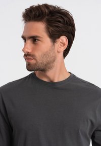 Donkergrijze lange mouwen T-shirt met een ronde hals en een gladde textuur; aansluitend ontwerp zonder zichtbare patronen of accenten.