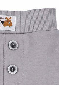 Szary bawełniany materiał z prążkowanym paskiem w talii. Posiada dwa okrągłe guziki oraz metkę wykonaną z materiału z rysunkiem płaskiej psiej buzi.