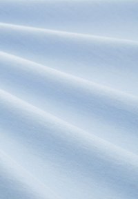 Šviesiai mėlynas medvilnės audinys su lygia tekstūra, pasižymintis subtiliomis raukšlėmis ir vienoda spalva, atspindinčia švelnią, natūralią šviesą.