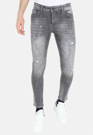 Slank gesneden grijze denim jeans met vervaagde plekken, versleten details en vijf-pocket ontwerp. Gepaard met witte sneakers.