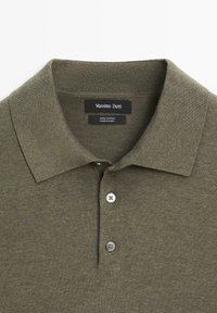 Polo in cotone verde oliva con colletto a punta, due bottoni bianchi e etichetta del marchio "Massimo Dutti" all'interno del collo.