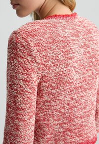 Maglione lavorato a maglia in rosso e crema, caratterizzato da un filato testurizzato, scollatura sfilacciata e una vestibilità ampia. Viene mostrato il retro senza chiusure.