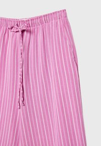 Pantalon en coton rose avec des rayures verticales blanches, doté d'une taille élastique et d'un cordon de serrage, ainsi que de poches latérales.