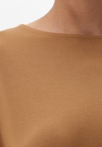 Brun kortærmet bluse lavet af glat strikket stof med en bred halsudskæring og delikat syning langs kanterne. Simple design, ingen mønstre.