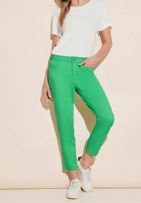 Gröna bomullsbukser med slim fit, fyra fickor och knappstängning. Kombinerat med en vit texturerad t-shirt och vita sneakers.