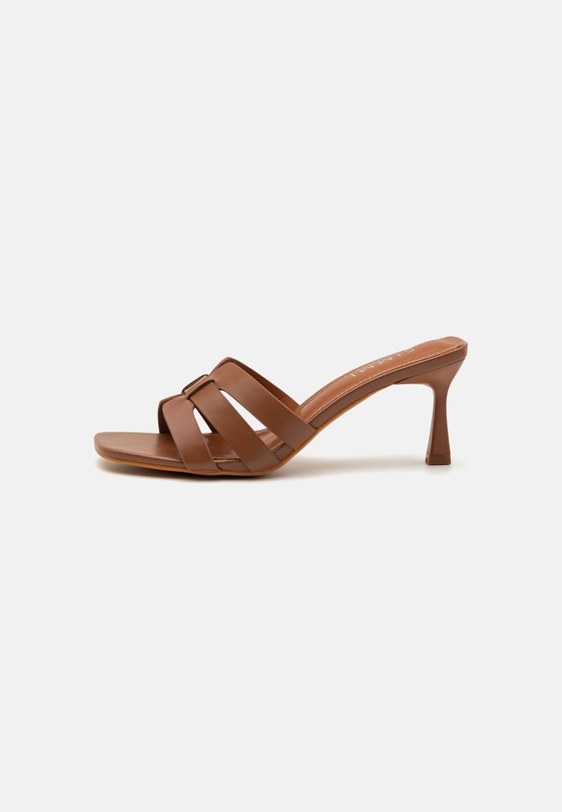 Brown heeled slide sandal with three overlapping straps, made of smooth leather, featuring a tapered heel and a wide square toe.