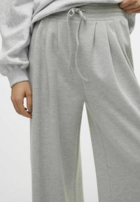 Lichtgrijze sweatpants van zacht materiaal, met plooien, een elastische tailleband met een trekkoord en een comfortabele pasvorm.