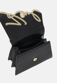 Schwarze Lederhandtasche mit goldfarbenem, wellenförmigem Hardware-Design, einem Druckverschluss und mehreren Innenfächern zur besseren Organisation.