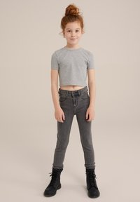 Grå kortärmad t-shirt, högmidjade mörkgrå jeans och svarta snörkängor. Slät bomullstyg, smal passform och klassisk femfickorsdesign.