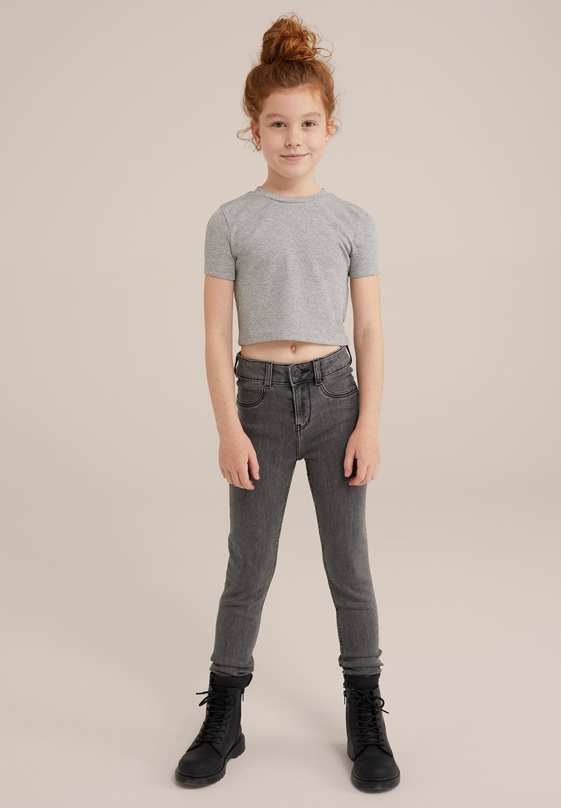 Grå kortärmad t-shirt, högmidjade mörkgrå jeans och svarta snörkängor. Slät bomullstyg, smal passform och klassisk femfickorsdesign.