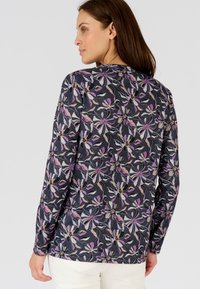 Maglietta a maniche lunghe in tessuto scuro con un motivo floreale che presenta dettagli in rosa, bianco e oro; scollatura rotonda e maniche aderenti.