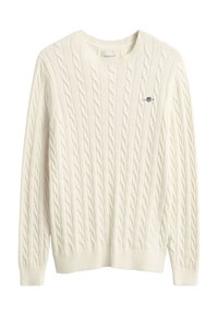 Maglione color crema a trecce con scollo rotondo, polsini e orlo a coste. Presenta un piccolo logo ricamato sul petto a sinistra.