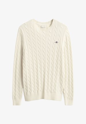 Kreemikas soonikkoes kampsun ümar kaelusega, soonikkoes mansettide ja äärega. Üles vasakul rinnal on väike tikitud logo.