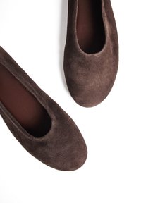 Ballerines en daim marron avec un bout rond et un design minimaliste, dotées d'une doublure intérieure lisse et d'une texture douce.