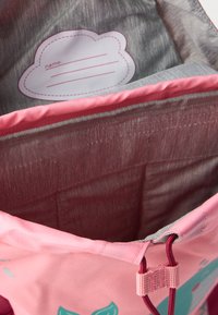 Borsa a sacchetto rosa con una texture liscia, con un interno grigio e un'etichetta con nome a forma di nuvoletta. Decorata con motivi di balene color acquamarina.