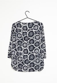Marinebluse mit weißem Blumenmuster, 3/4-Ärmel, abgerundetem Saum, leichtem Stoff und lässiger Passform, hängt an einem schwarzen Haken.