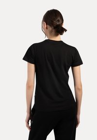 Camiseta negra de manga corta, hecha de algodón, con un cuello redondo y un diseño ajustado. Sin patrones ni acentos visibles.
