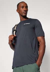 Dark gray short-sleeve athletic shirt with a round neck, made of lightweight fabric, featuring a mesh side panel and 'TERREX' logo.