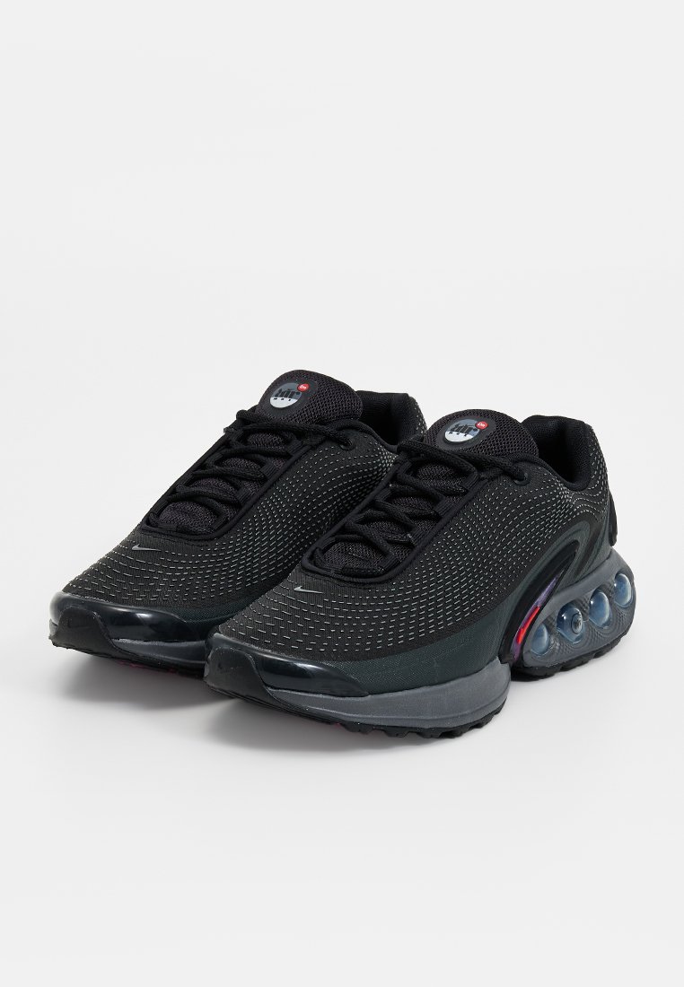 Une paire de baskets de sport noires avec des dessus texturés, des lacets noirs et des coussinets de soutien transparents dans la semelle grise.