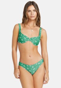 Grönt bikinitset med blommönster, vadderad underwire-topp med breda axelband och matchande sidbandat underdel, tillverkat av texturerad tyg.