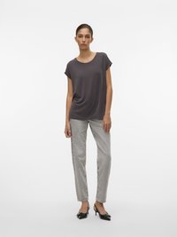 Mørkegrå kortærmet top i afslappet pasform, parret med lysegrå lige ben jeans og sorte højhælede sko med sløjfedetalje.