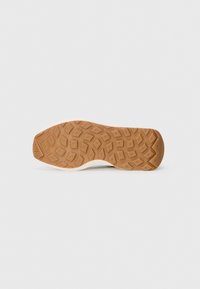 Gummisohle in Tan mit einem strukturierten, geometrischen Muster; weiße Zwischensohle mit glatter Oberfläche; keine sichtbaren Marken oder Logos.