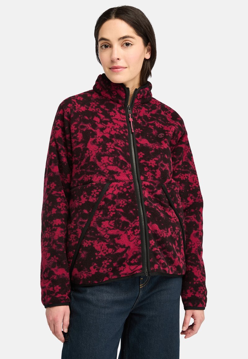Giacca in pile con un motivo astratto rosso e nero, dotata di colletto alto, zip frontale e tasche laterali, caratterizzata da una texture resistente.