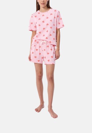 Ensemble de pyjama en coton rose comprenant un haut à manches courtes et un short, tous deux ornés de motifs en forme de cœurs rouges répétés. Comprend une taille élastiquée avec cordon.