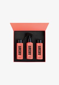 Set di tre prodotti per la cura dei capelli in bottiglie corallo etichettate "Shampoo", "Trattamento alla Cheratina" e "Balsamo", in una scatola rosa con interno nero.