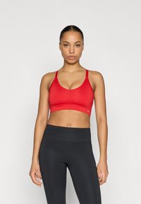 Red sports bra with a smooth texture, v-neck design, and adjustable straps, paired with black high-waisted leggings.