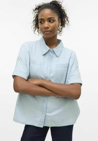 Camicia azzurra a maniche corte in cotone con chiusura a bottoni, due tasche sul petto e vestibilità rilassata. Tessuto morbido e collo classico.
