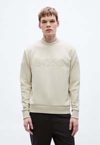 Αν�οιχτό μπεζ φούτερ με ανάγλυφο λογότυπο "BOSS" στο μπροστινό μέρος. Διαθέτει στρογγυλή λαιμόκοψη και ριμπ μανσέτες και τελείωμα. Μαλακή υφή.