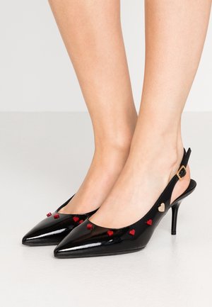 Sorte slingback stiletter i laklæder med spidse snuder, dekoreret med små røde hjerteformede pynt og en guldbøjle på ankelremmen.