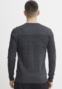 Pullover griș închis, realizat dintr-un țesătură texturată, cu dungi orizontale pe spate și mansete și tiv din tricot cu nervuri.